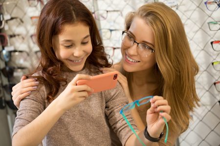 MoneyCheck | Concordia Brillenversicherung, Frau und Tochter mit Handy MoneyCheck | Concordia Brillenversicherung